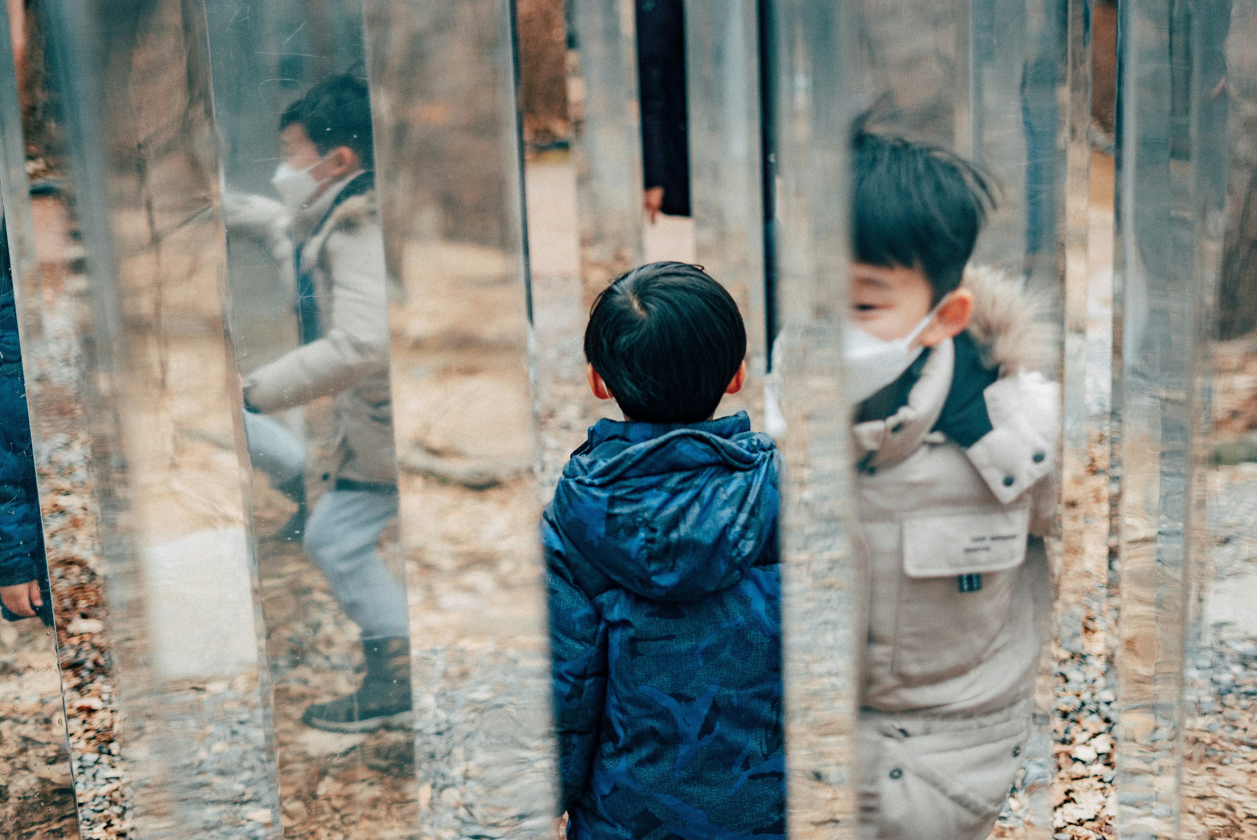 boy in blue jacket standing beside glass window